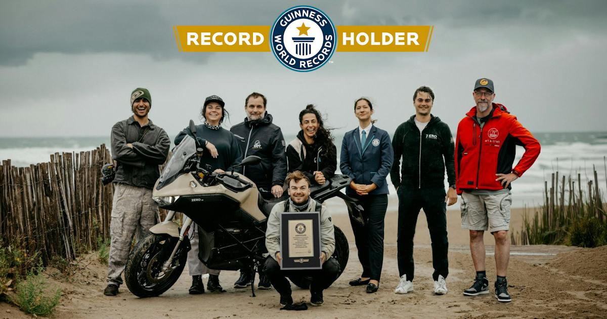 Zero-Team mit Motorrad und Guinness-Urkunde am Meer nach der gemeldeten Rekordfahrt